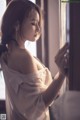 A woman in a white shirt leaning against a window.